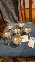 Photo showing six sterling silver dessert cup bases holding glass dishes and the sterling handled bell.