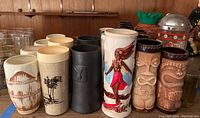 Front view of entire assortment showing ceramic mugs, plastic tumblers, metal-sleeved glass and clear glassware