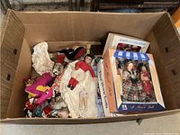 Box with assorted vintage dolls and plush items visible inside