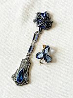 Full view of the necklace and brooch on a white fabric surface showing design details.