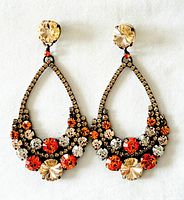 Front view of both earrings showing colourful round faceted glass crystals in amber, orange, clear shades on a dark metal frame.