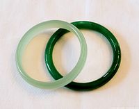 Two jade bangles overlapping on white background