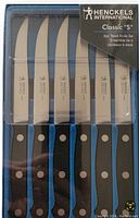 Front image of the six Henckels steak knives set in original clear plastic packaging, showing the blade and handle design.