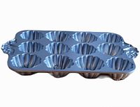 Angled view of the Nordic Ware muffin pan showing the pumpkin-shaped cavities and leaf handles on the side.