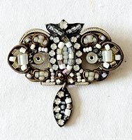 Front view of ornate brooch showing bead and crystal decoration with dangling bead.