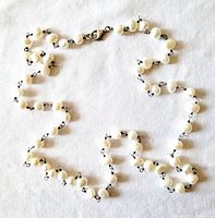 White freshwater pearl necklace laid out loosely showing pearl details and silver link closures.