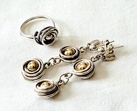 Top view of both the ring and earrings showing the silver swirl design and gold beads in the center.