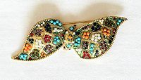 Front view of gold-tone bow brooch showing colorful beads and crystals in geometric sections.