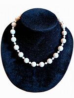 Front view of the full necklace displayed on a black velvet bust, showing faceted white glass beads and clasp.