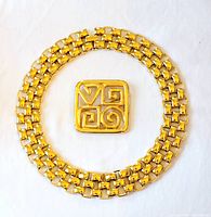 Both the necklace and brooch displayed side by side on white background, showing gold-tone color and signed condition.