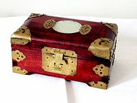 Angled view of the vintage wooden box with brass accents and oval green stone on top.