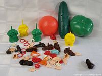 Photo of Mr. Potato Head toy components showing vegetable-shaped plastic bodies and many small accessories spread out flat