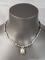 Front view of the necklace on a display bust showing the turtle pendant and bead pattern