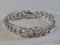 Full view of the sterling silver charm bracelet laid flat showing the chain design and clasp.