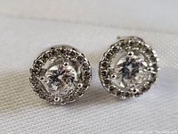 Close up front view of one sterling silver stud earring with central round clear stone and halo of smaller clear stones