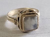 Close-up side angle showing square raw quartz and ornate beaded bezel setting on sterling silver ring.