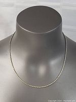 Full length view of the sterling silver rope chain necklace displayed on a grey mannequin bust showing the chain's fine twisted rope design and link structure.