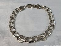 Full view of thick sterling silver bracelet on white surface.