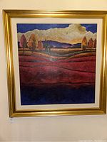 Framed art print showing textured landscape with red hills and cloudy sky