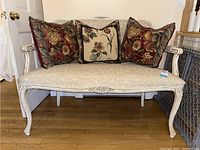 Front view of upholstered bench with three decorative accent pillows in dark red floral tapestry and cream embroidered design.