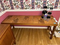 Console table placed against a wall with floral wallpaper and pink painted lower wall. Table has several blender cup accessories that are not included in the lot.