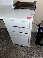 First white IKEA file cabinet with three drawers and black caster wheels.