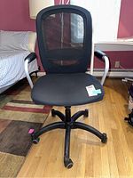 Front view of the black office chair showing mesh back, padded seat, armrests and five-legged wheeled base.