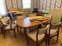 Six teak dining chairs arranged around table in a room setting