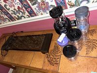 Ninja Professional blender base, multiple blending cups with lids, purple shaker cup, and Salton warming tray on tile surface