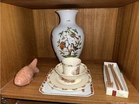 Wide shelf view showing the porcelain vase, dishware pieces, fish figurine, and chopsticks in box