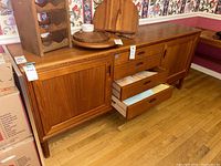Front view of the wooden sideboard showing three drawers center and cabinet doors at each end