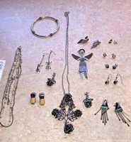 Top-down view of the jewelry lot, showing necklace, bracelet, and various styles of earrings including rose cross pendant and silver angel pendant