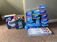 Photo of entire lot showing Ziploc boxes, Lysol toilet cleaner box, Windex cleaner bottles, and parchment paper boxes arranged on carpet.