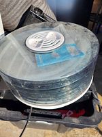 Photo showing the stacked transparent trays of the food dehydrator with vented silver metal plate on top.
