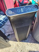 Front view of black electric tower heater showing vent grill and control panel with digital timer and buttons.