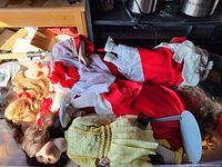 Multiple porcelain dolls in a bin, dressed in traditional and vintage outfits, showing the mix of clothing styles and hair colors.