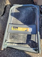 Photo showing the gray metal frame of Burris moving cart with a label indicating 160 lb capacity and a folding handle resting on the ground.