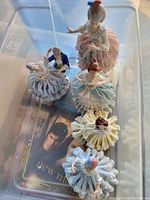 Photo showing six porcelain figurines in pastel-colored traditional attire with detailed ruffled skirts.