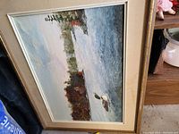 Full view of framed landscape painting showing water with duck and trees in autumn colors.