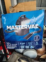Mastervac branded box showing specifications including 10L capacity, 2 HP motor, 1.75 inch hose diameter, and 8 ft hose length.