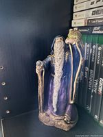 Wizard figurine on a shelf next to a row of Xbox and PlayStation game cases