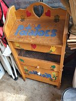Front view of wooden potato and onion box showing hand-painted text and decorative elements