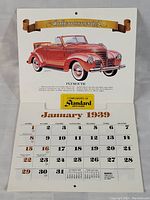 Full view of the calendar opened to show January 1939 with Plymouth car illustration and Standard Auto Glass promo
