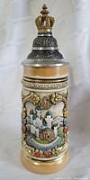 Front side view of vintage German beer stein showing detailed relief artwork of Neuschwanstein castle with floral and ornamental decorations beneath an ornate crown lid.