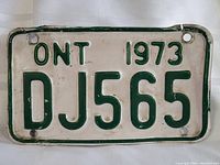 Front view of 1973 Ontario off road vehicle metal license plate with registration number DJ565. Shows wear and age marks.
