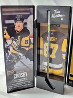 Front angled view of the mini hockey stick in box, showcasing the stick and image of Sidney Crosby in Penguins uniform.