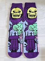 Pair of adult socks with Skeletor character design showing front side with detailed pattern and colors.