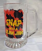 Photo showing front side of the glass beer mug with 'SNAP INTO A SLIM JIM' text on colorful red and black background.