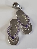 Photo front angle showing the sterling silver flip-flop shoe pendant with purple stones on straps.