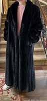 Front view of black full-length fur coat on model